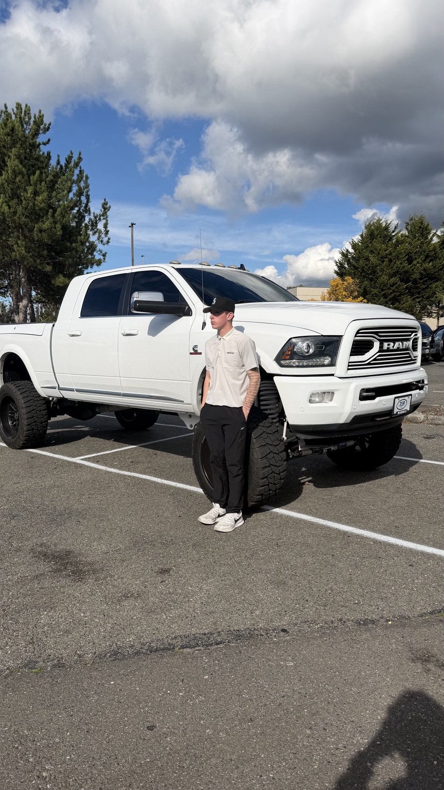 Tyas Selby in his Aptive polo standing beside his white Ram truck